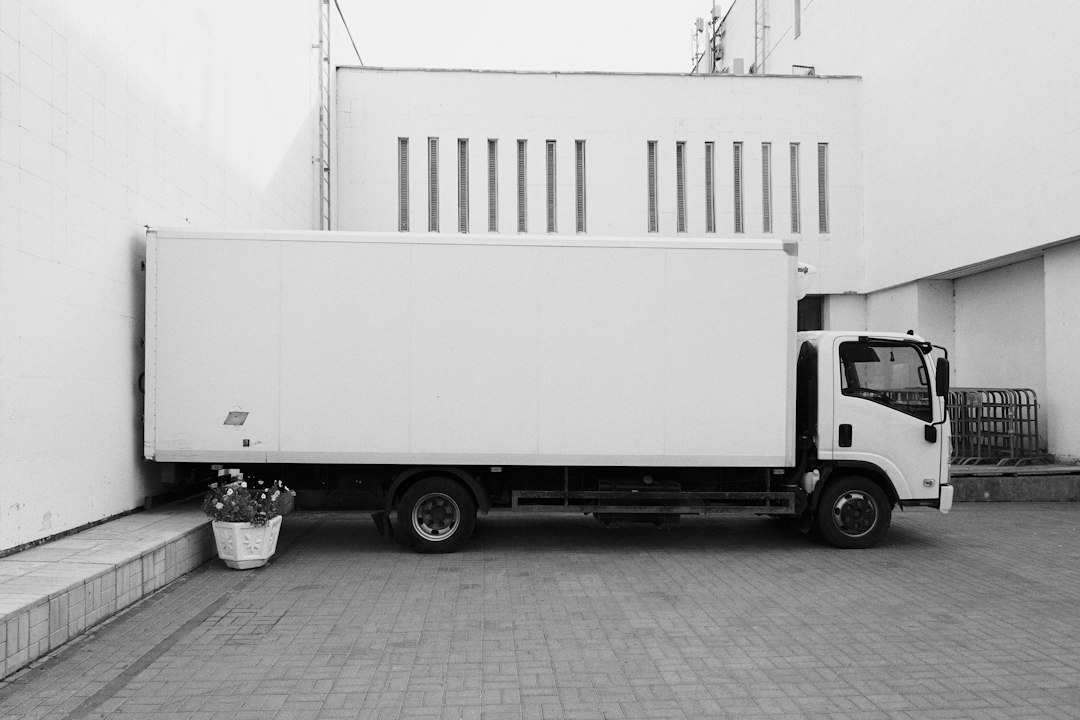 White delivery truck at a commercial building, illustrating temperature-controlled courier transport.